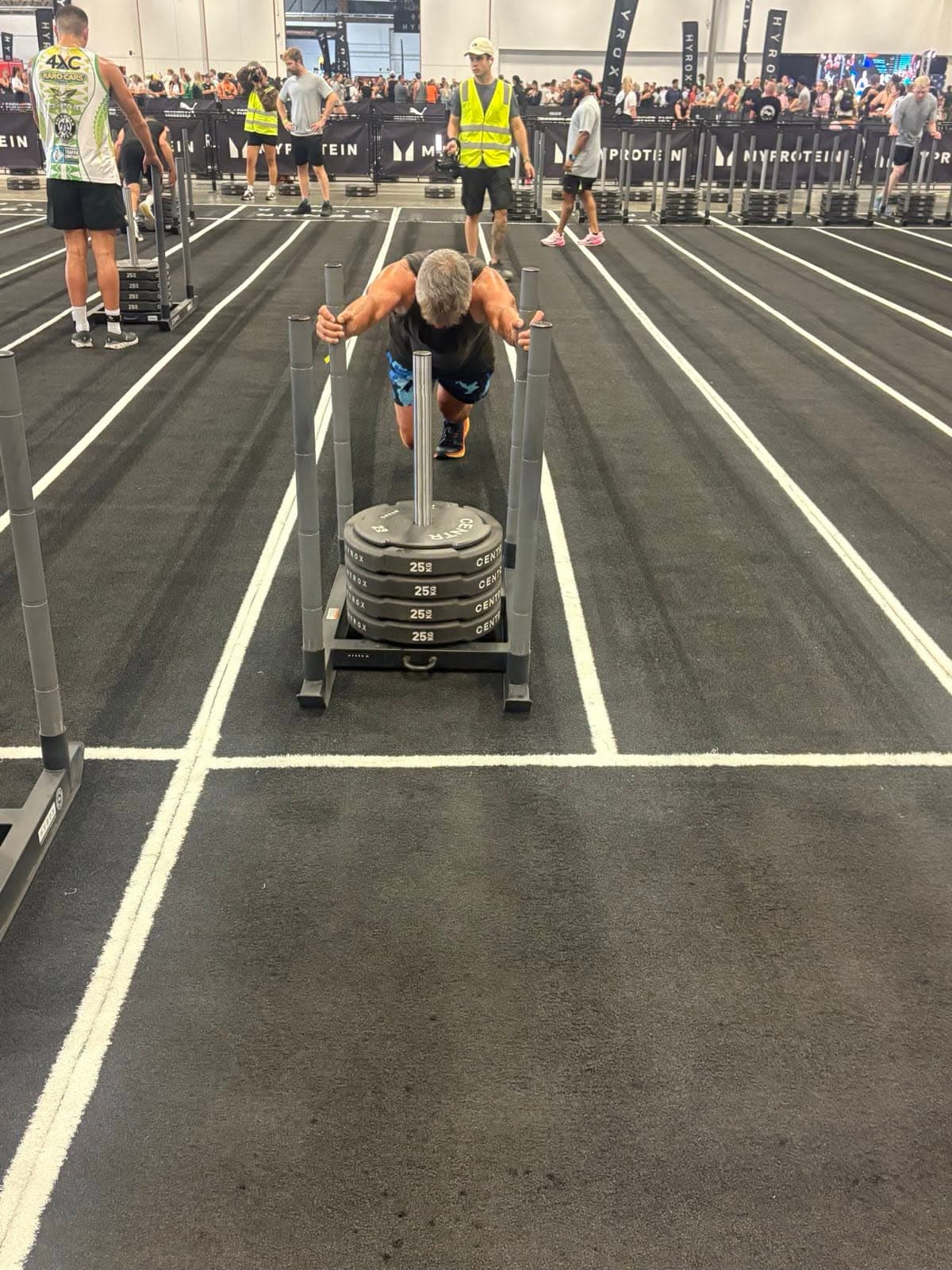 An athlete driving a weighted sled down the lane.